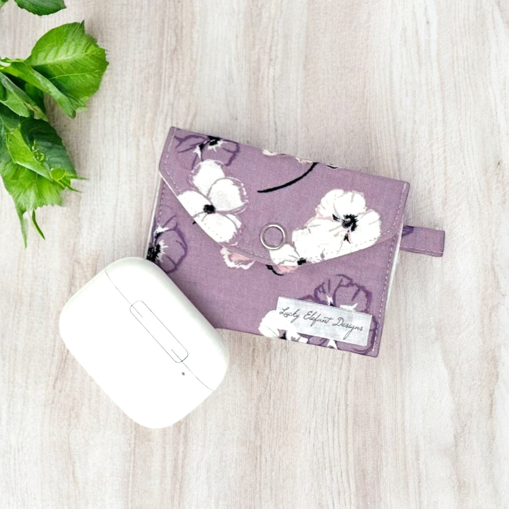 Lavender floral fabric AirPods case on wooden surface