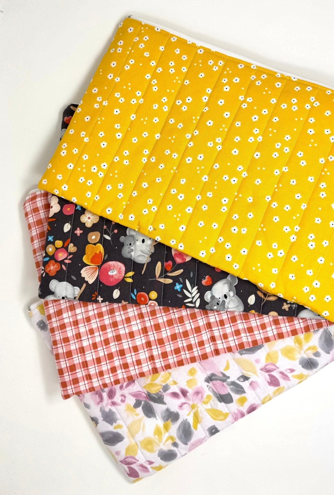 Quilted laptop sleeves in multiple fabric patterns including floral, gingham, and bright prints, showing available design options
