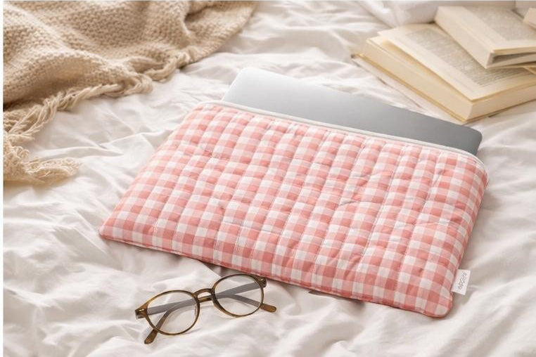 Pink gingham quilted laptop sleeve holding a laptop on a cozy bed, soft padded protective case for everyday use