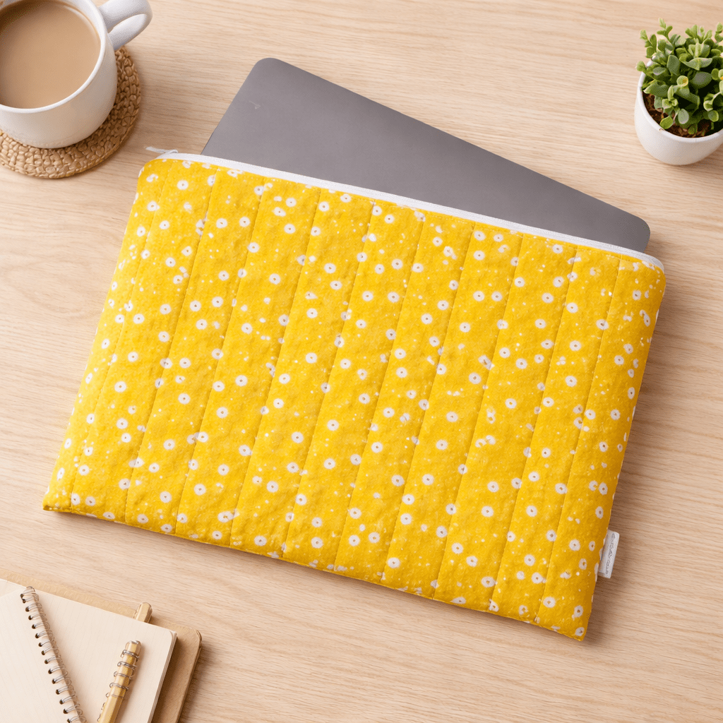 Yellow floral quilted laptop sleeve on desk with laptop and accessories, padded protective case for everyday use